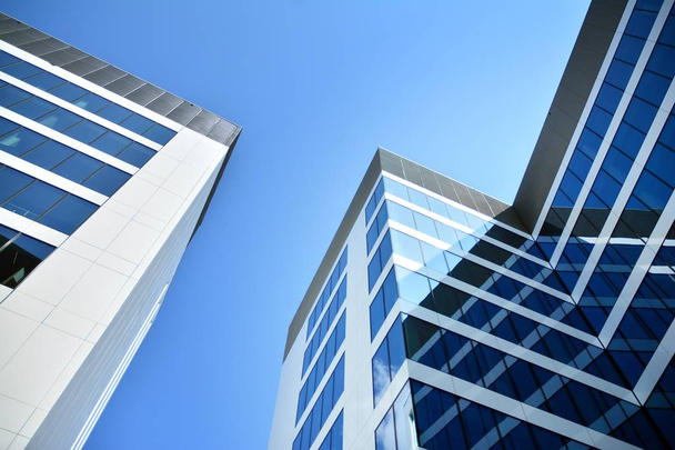 New office building in business center. Wall made of steel and glass with blue sky. Modern corporate architecture - business and success concept. - Photo, Image