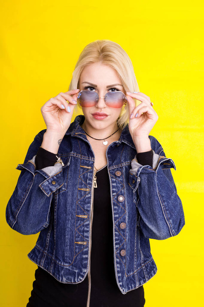 beautiful blonde girl in a denim jacket is smiling on a yellow b - Photo, image
