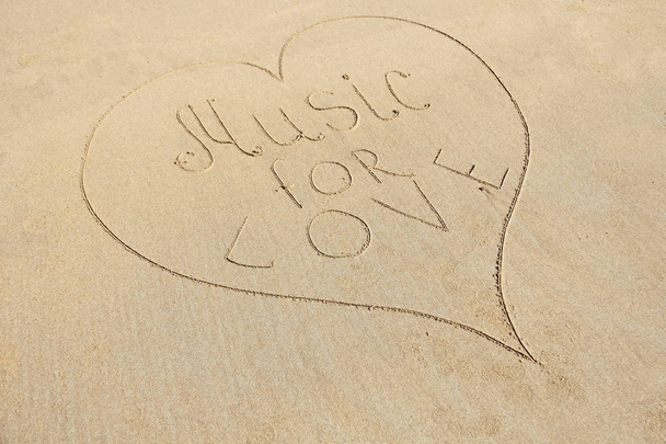 die Inschrift Musik für die Liebe wird in den Sand gezeichnet und ist surro - Foto, Bild