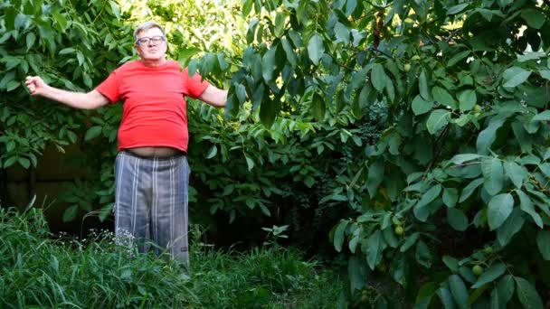 Senior man in Casual kleding, misschien een gepensioneerde, Oefeningen of gymnastiek in de achtertuin of in de tuin. Gebruik als een gezonde levensstijl voor mensen van middelbare leeftijd. - Video