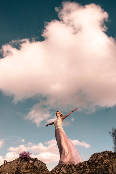 Girl in an evening dress in the mountains against a cloudy sky - 写真・画像