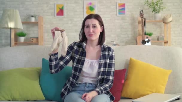 young woman holds socks in her hands and feels an unpleasant smell - Materiaali, video