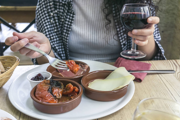Femme au restaurant mangeant des hors-d'œuvre et tenant un verre de vin rouge
 - Photo, image