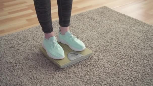 Concetto di controllo del peso, piedi delle donne sulla bilancia del pavimento in soggiorno
 - Filmati, video