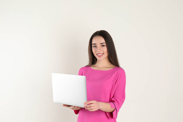 Portrait of young woman in casual outfit with laptop on light background - Photo, image