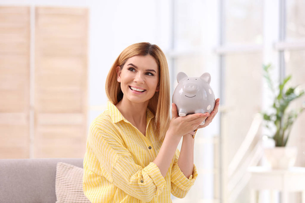 Portrait of woman with piggy bank at home - Foto, Imagem