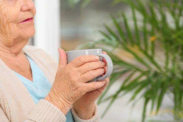 Closeup view of elderly woman with cup of tea in nursing home, space for text. Assisting senior generation - Fotografie, Obrázek