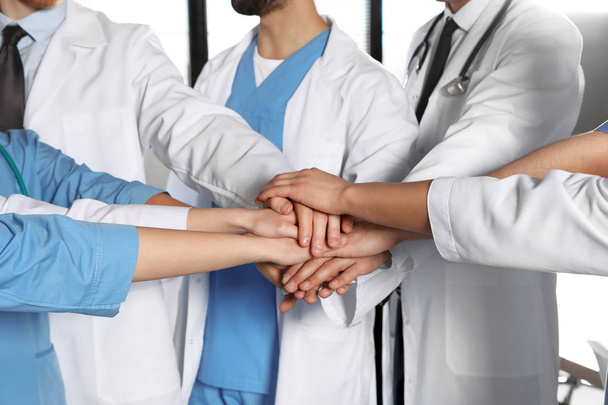 Team of medical workers holding hands together, closeup. Unity concept - Fotografie, Obrázek