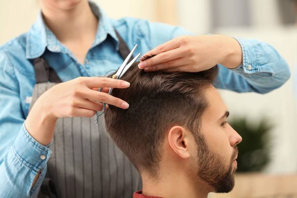 Barber making stylish haircut with professional scissors in beauty salon - Zdjęcie, obraz