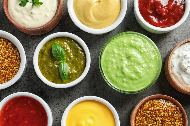 Set of different delicious sauces on grey table, top view - Foto, afbeelding