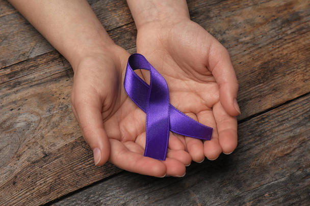 Woman with purple awareness ribbon on wooden background, closeup - Fotoğraf, Görsel