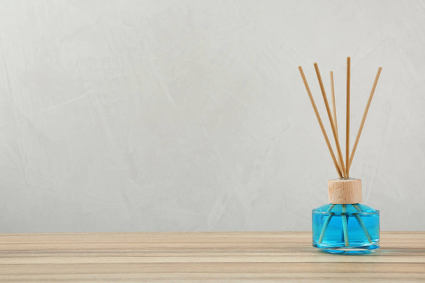 Reed air freshener on wooden table against grey background, space for text - Φωτογραφία, εικόνα