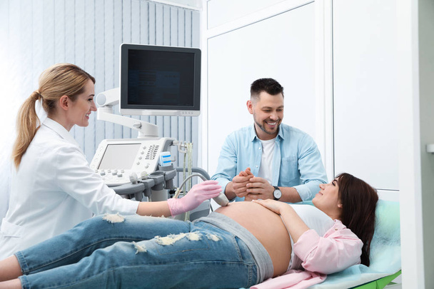 Man supporting his wife during ultrasound scan in clinic - Фото, зображення