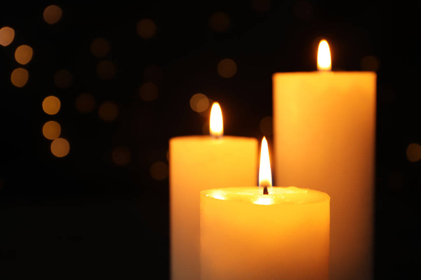 Burning candles on black background with blurred lights, space for text - Fotografie, Obrázek