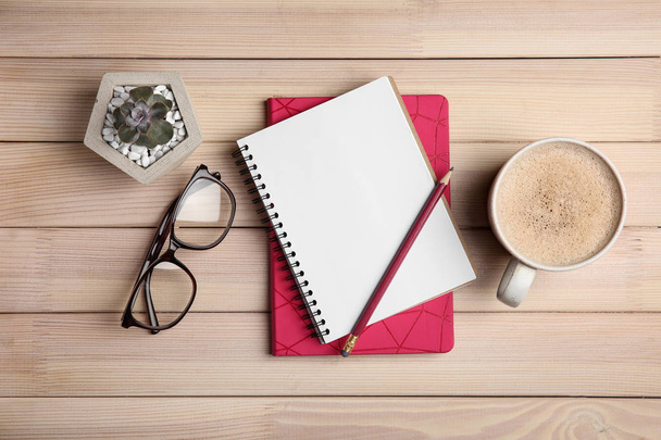 Flat lay composition with office stationery and cup of coffee on wooden table - Foto, imagen