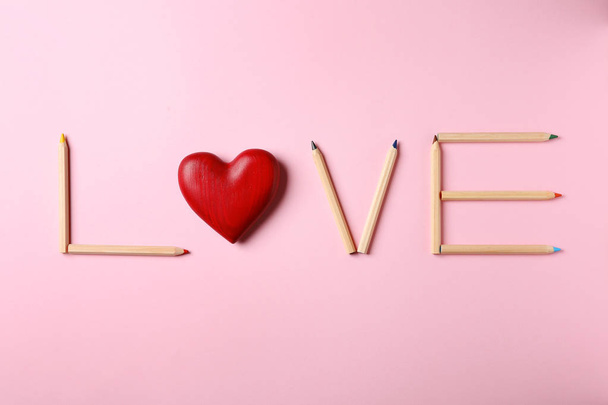 Word LOVE made of pencils and decorative heart on pink background, flat lay - Fotoğraf, Görsel
