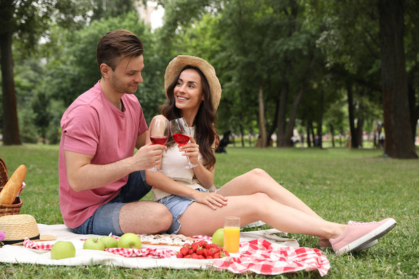 Happy young couple having picnic in park on summer day - Φωτογραφία, εικόνα
