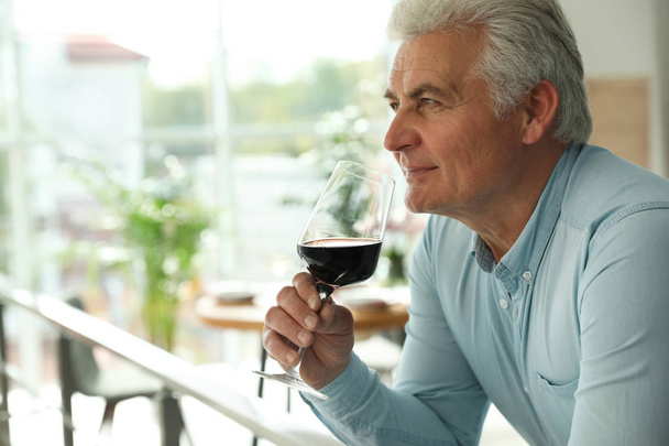 Senior man with glass of wine in restaurant. Space for text - 写真・画像