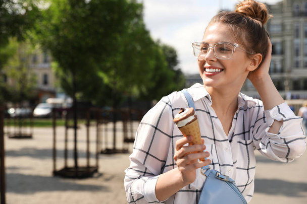 Young happy woman with ice cream cone on city street. Space for text - Φωτογραφία, εικόνα