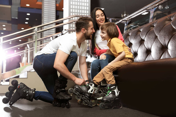 Happy family putting on roller skates indoors - Photo, Image