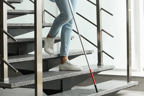 Τυφλό άτομο με μακρύ ζαχαροκάλαμο πηγαίνει κάτω σκάλες σε εσωτερικούς χώρους, κοντινό πλάνο - Φωτογραφία, εικόνα