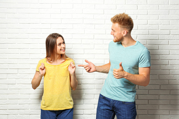 Young couple wearing blank t-shirts near white brick wall. Mockup for design - Fotó, kép