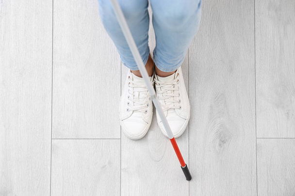 Blind person with long cane standing indoors, top view - Foto, Bild