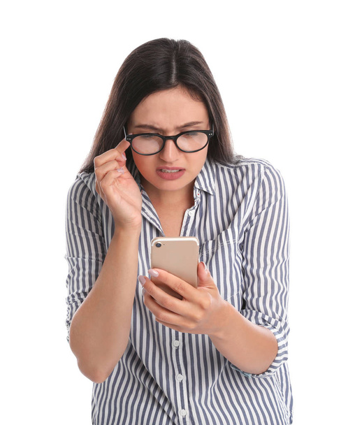 Young woman with glasses using mobile phone on white background. Vision problem - Fotografie, Obrázek