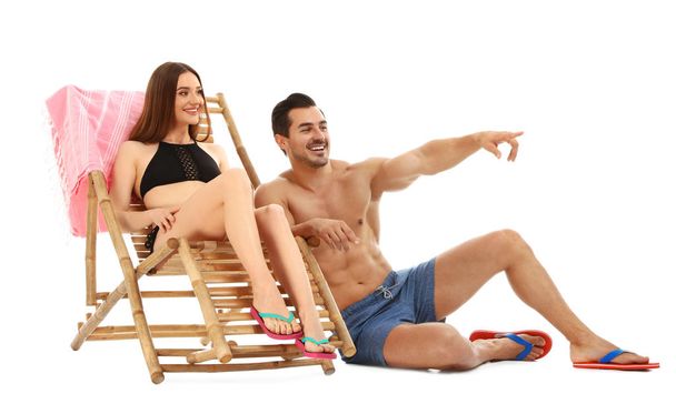 Young couple with sun lounger on white background. Beach accessories - Fotoğraf, Görsel