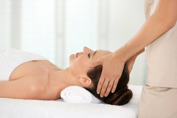 Beautiful young woman enjoying massage in spa salon - Фото, изображение