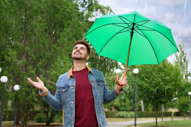Man with umbrella outdoors on rainy day - 写真・画像