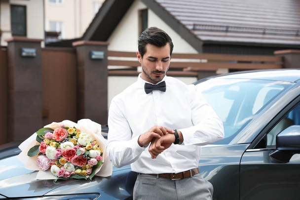 Young handsome man with beautiful flower bouquet near car outdoors - Фото, зображення