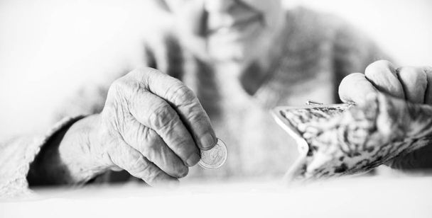 Yksityiskohtainen lähikuva kuva tunnistamaton iäkkäiden naisten kädet laskenta jäljellä kolikoita hänen lompakko maksettuaan laskuja. Musta ja valkoinen kuva
. - Valokuva, kuva
