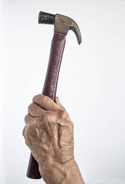 Mano izquierda de la mujer mayor sosteniendo el martillo sobre fondo blanco, construcción de construcción y reparación de concepto de herramienta
 - Foto, imagen