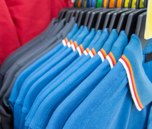 Mode-Kleidung auf Kleiderständern - bunte Kleiderschränke. Nahaufnahme der farbenfrohen Auswahl trendiger Männermode auf Kleiderbügeln im Kleiderschrank oder Einkaufszentrum. - Foto, Bild