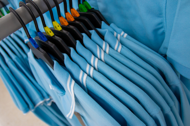 Divatcikkek a ruházati rack-világos színes szekrényben. Közeli fel színes választéka divatos férfi kopás a akasztók a boltban szekrényben vagy bevásárlóközpontban. - Fotó, kép