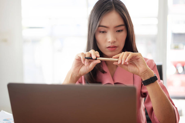 Молода азіатська бізнес-леді перевіряє час, працює з ноутбуком
 - Фото, зображення