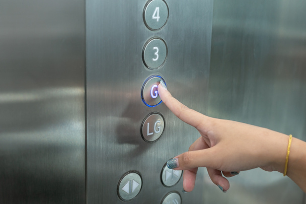 クローズアップワマン手はエレベーターのアップボタンを押します. - 写真・画像
