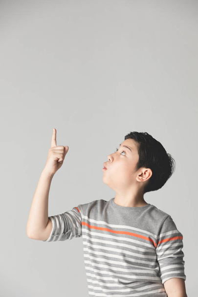 Nuori aasialainen poika ajattelee ja osoittaa hymyillen kopioi sp
 - Valokuva, kuva