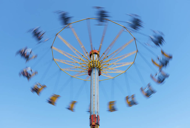 kolotoč v pohybu v zábavním parku s modrým oblohou pozadí - Fotografie, Obrázek