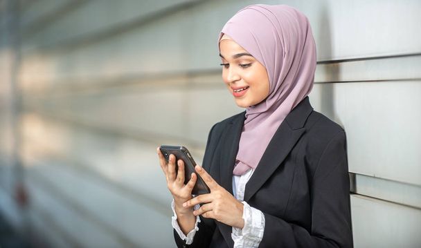 Young Female Muslim Entrepreneur looking at her smartphone. Shal - Foto, afbeelding