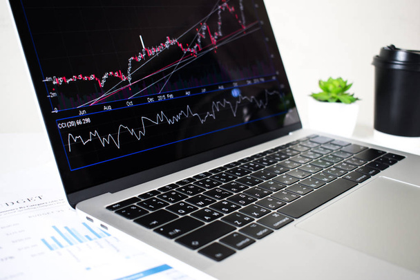 A laptop számítógép képernyője pénzügyi táblázatokat és grafikonokat jelenít meg  - Fotó, kép