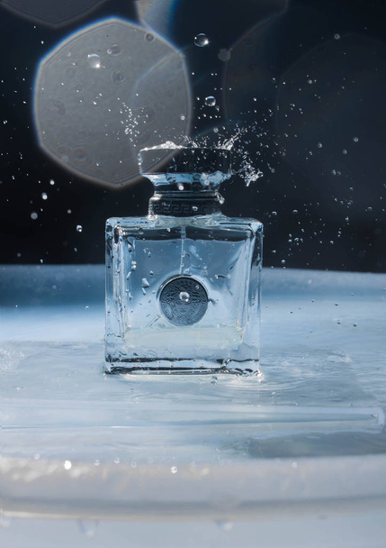 Rusia, Udachnyy, 08 / 01 / 2019. Eau de toilette, perfume Versace sobre un fondo oscuro y un sustrato azul de agua. Con hermosas salpicaduras de agua
.  - Foto, imagen