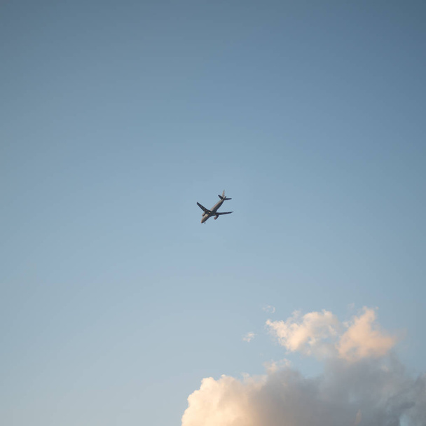 日没時に雲を背景に空を飛ぶ飛行機 - 写真・画像