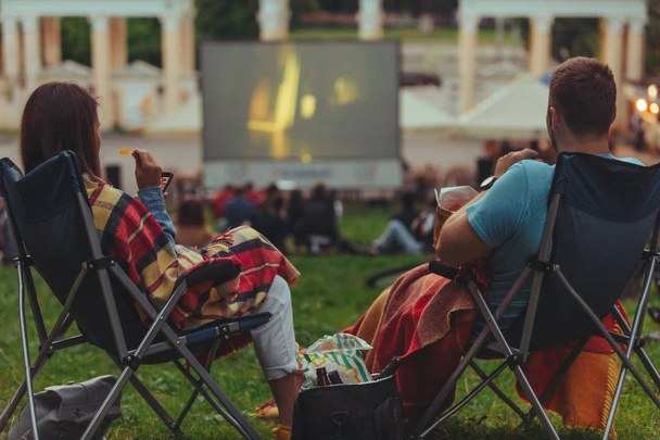 couple assis dans des fauteuils de camp dans le parc de la ville regardant le film en plein air au cinéma en plein air
 - Photo, image