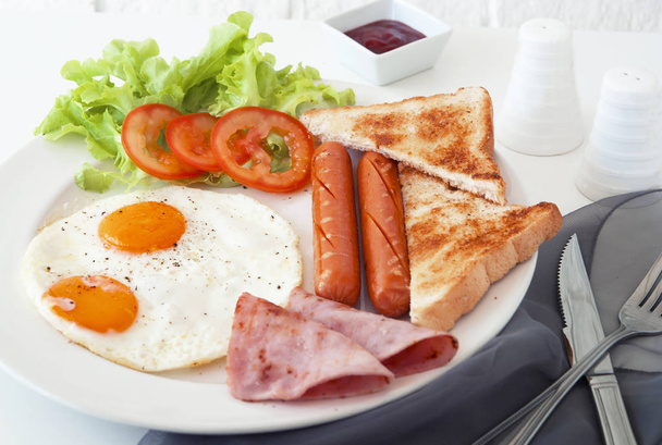 Morning breakfast, Fried egg, sausage and ham in white dish on table together light in the morning - Photo, Image