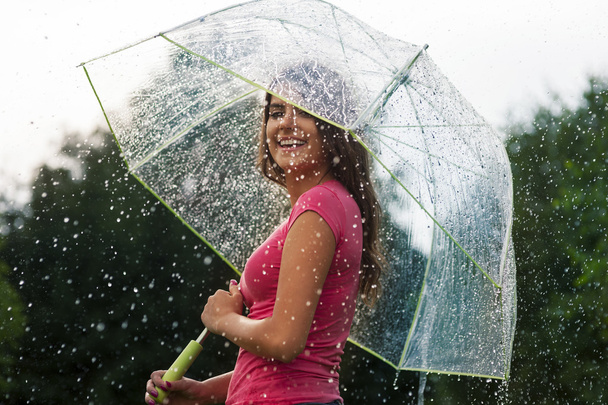 νεαρή γυναίκα να στέκεται στην καλοκαιρινή βροχή με ομπρέλα - Φωτογραφία, εικόνα