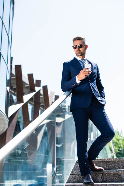 handsome man in suit with hand in pocket using smartphone  - Фото, изображение
