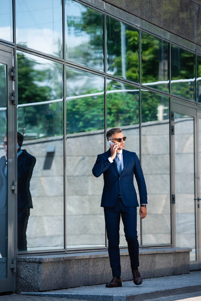 takım elbiseli yakışıklı adam ve gözlük akıllı telefonda konuşurken  - Fotoğraf, Görsel