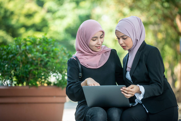Muzułmańskich koleżanek patrząc na laptopa razem. Odkryty shoo - Zdjęcie, obraz